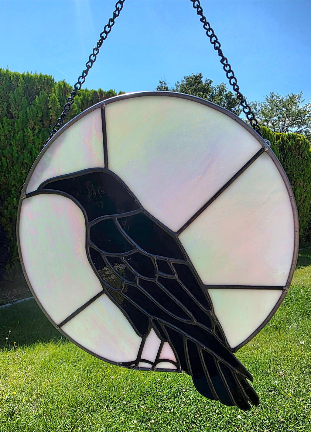 Raven Moon handcrafted raven stained glass panel with black and iridescent opalescent glass shown in natural light