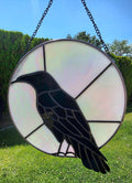 Raven Moon handcrafted raven stained glass panel with black and iridescent opalescent glass shown in natural light