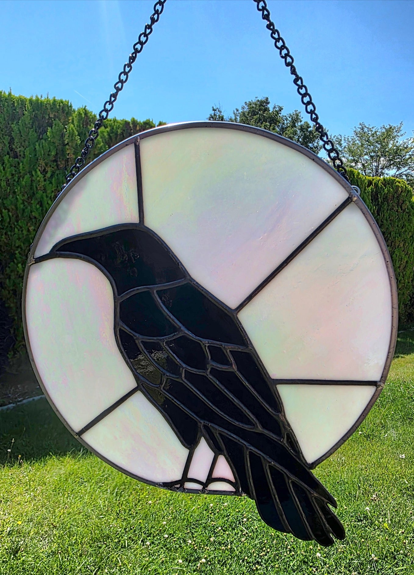 Raven Moon handcrafted raven stained glass panel with black and iridescent opalescent glass shown in natural light